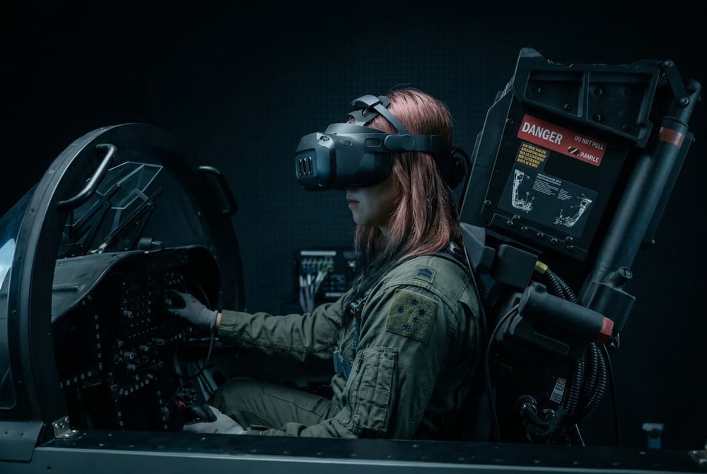 A pilot in a flight suit at the controls of a Rotorix simulator, wearing a mixed-reality headset with the system pack mounted behind the seat.